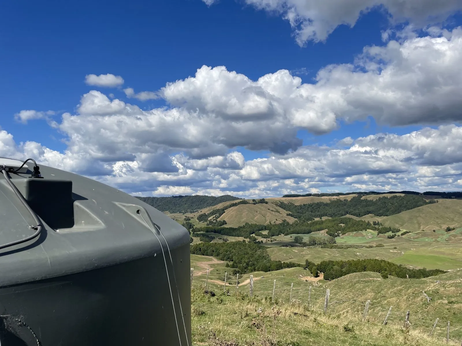 A Knode tank level sensor fitted on top of a farm water tank, overlooking hill country